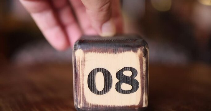 A child's wooden cube with the number eight approaches the frame. Close-up of the number 8. A toy with the number eight. The number eight is burnt into the wood