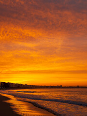 Amazing view of a fiery sunrise with multicolored clouds. Sea waves along the seashore at sunrise. Morning time. Ocean view. La Baule-Escoublac, France