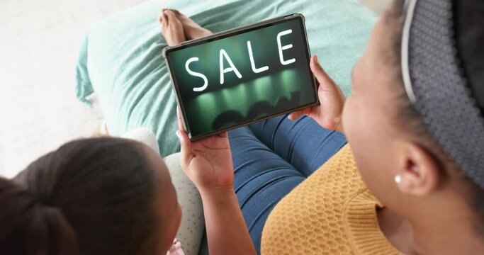 African american mother and daughter using tablet, online shopping during sale, slow motion