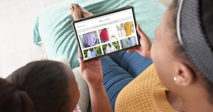 African american mother and daughter using tablet, online shopping for clothes, slow motion