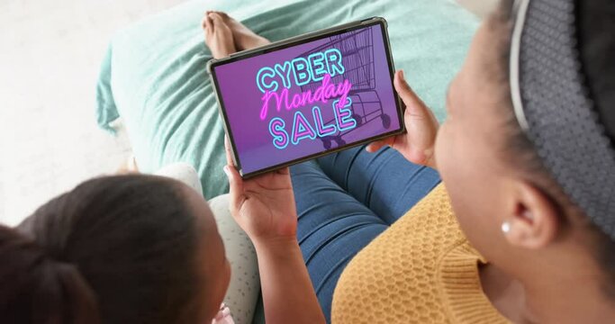 African american mother and daughter using tablet, online shopping on cyber monday, slow motion