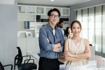 Successful happy asian businessman and businesswoman smiling arms crossed standing at modern office looking at camera. business professional teamwork for support partnership.
