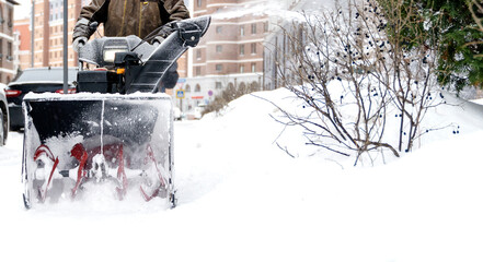 snowblower removes snow, a man cleans the yard outside