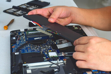 computer technician laptop motherboard repair technician Removing the battery from the notebook...