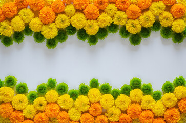 Decorative rangoli made from colorful marigold flowers and green Chrysanthemum for Diwali festival on white background with space for text.