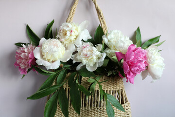 pink and white peonies in a summer woven bag close-up. floral background, natural backdrop. no plastic concept.