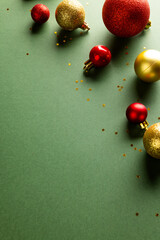 Vartical image of christmas red and gold baubles with copy space on green background