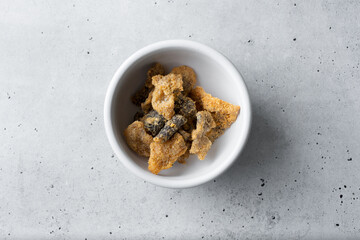 A top down view of a bowl of deep fried salmon skin.