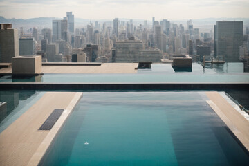 Fototapeta na wymiar an amazing view of a swimming pool on a rooftop apartment surrounded by buildings