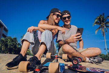 Young happy couple with skateboards taking selfie at the skatepark