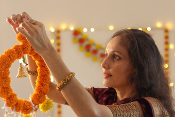 Beautiful Indian woman decorating home with flowers for the festival of Diwali. Life style image...