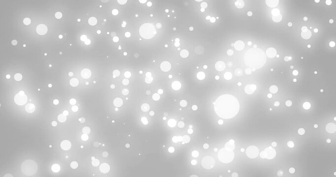 Glowing white christmas light particles falling on grey bokeh background
