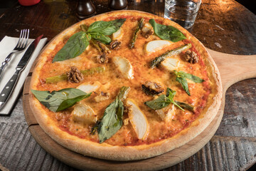 A pizza with walnuts, asparagus, apples and basil.