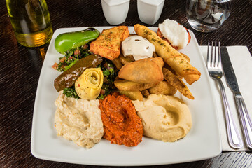 A vegeratarian plate with mixed vegetables, rice, hummus, and fried breads.