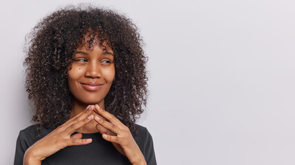 Hideous curly haired woman steeples fingers and makes up good idea ponders on something dressed...