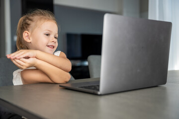 Little girl does finger gymnastics online on the laptop home. Distance learning concept.