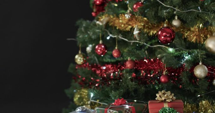 Video of christmas tree with presents and fairy lights with copy space on black background