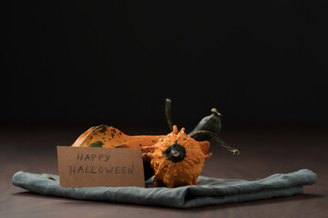 decorative pumpkins on walnut wood table with Happy Halloween card