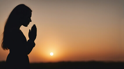 Silhouette of a praying girl with folded palms at sunset - obrazy, fototapety, plakaty