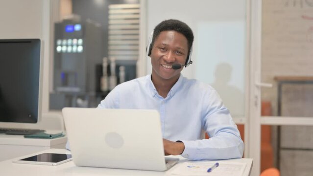 Thumbs Up by African Man with Headset Using Laptop in Call Center