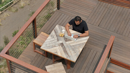 aerial view of man in cafe and using laptop while surrounded by nature