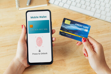 Hand holding credit card and using smartphone with scan fingerprints to confirm your login to mobile wallet application, credit card online. - obrazy, fototapety, plakaty
