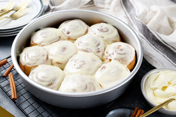 Homemade cinnamon buns with cream cheese icing in backing pan.