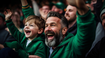 Irish father and son in stands, filled with enthusiastic supporters of rugby or football team wearing green clothes to support national sports team - Powered by Adobe