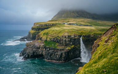 Dramatic view of Mulafossur waterfall with Gasadalur village on background. Vagar island, Faroe...