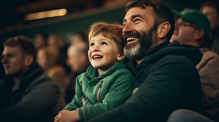 Irish father and son in stands, filled with enthusiastic supporters of rugby or football team...