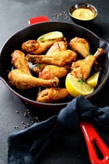 Juicy Oven Roasted Chicken legs in red iron pan.  Black background