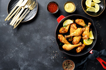 Juicy Oven Roasted Chicken legs in red iron pan. Black background, top view