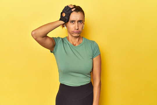 Athletic middle-aged woman on yellow backdrop being shocked, she has remembered important meeting.