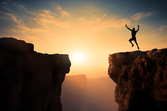 silhouette of person jumping on top of a mountain cliff symbolizing success