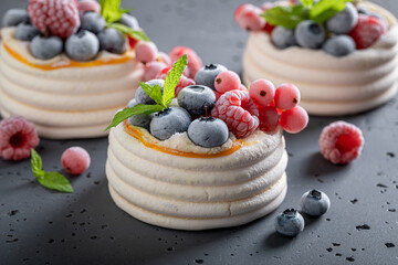 Sweet mini Pavlova dessert with frozen fruit and whipped cream.