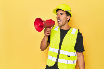 Worker in yellow shouting through megaphone on yellow.