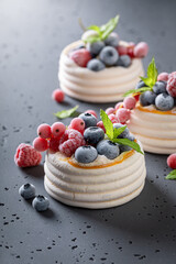Creamy mini Pavlova dessert with frozen fruit and whipped cream.