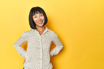 Young Chinese lady, yellow studio background happy, smiling and cheerful.