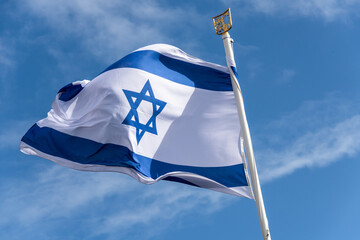 Israelische Nationalflagge mit dem Judenstern im Wind flatternd vor blauem Himmel - 662181252