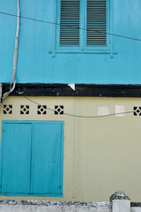 Close up photo of two storey old house with blue paint wooden windows. 