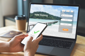 Hand using laptop and booking hotel on website for vacation after a long work and payment completed...