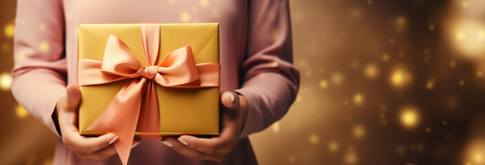 Female hands holding golden christmas or birthday gift or present with ribbon. Coupon and voucher concept. With copy space. - obrazy, fototapety, plakaty