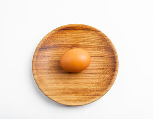 Wooden eco-friendly tableware for healthy lifestyle design. A chicken egg lies on a wooden plate.