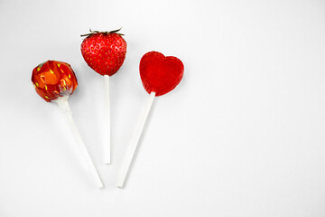 3 Erdbeer-Lollies, eine echte Erdbeere auf einem Lollistiel und zwei Erdbeerlollies, einer rund und...