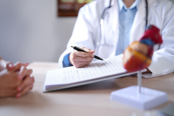 Asian cardiologist doctor women pointing on document to explaining about health examination results to female patient while giving counseling about medical and mental health therapy in clinic