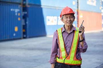 senior factory worker or engineer holding walkie talkie in containers warehouse storage