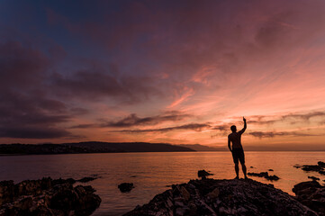Wschód słońca nad morzem. Fotografia motywacyjna. Poranek ze wschodem słońca. Sylwetka mężczyzny na tle wschodzącego słońca. 