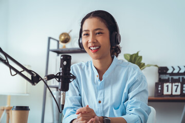 Young Asian woman use microphones wear headphones with laptop record podcast interview for radio....