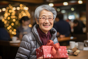 Older woman asian japanese chinese happy and smiling with a gift at Christmas time