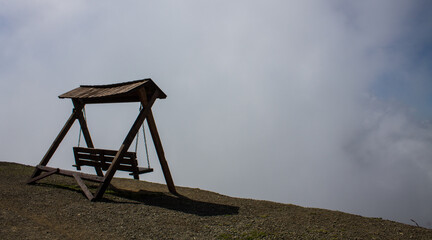 Wooden swing on the mountainside against the backdrop of a dramatic cloudy sky and a space to copy